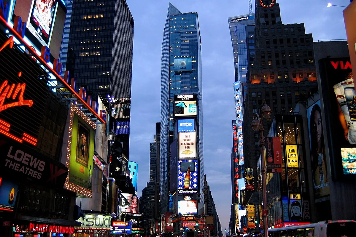 Times Square hotel area at dusk with theater lights, hotel entrances and travelers.